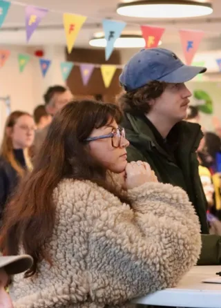 Een groep deelnemers zit in een kleurrijk versierde ruimte met vlaggetjes tijdens de Dag van de Beroepskracht.