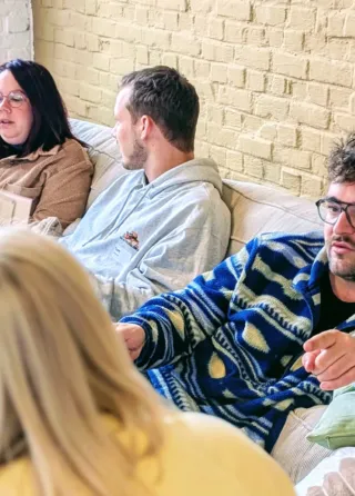 Een groep ervaren jeugdwerkers zit samen in gesprek op de zetel tijdens een reflectietraject.